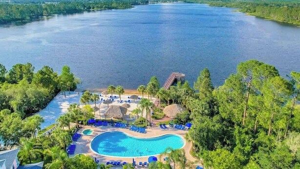 A resort with a large swimming pool, lounge chairs, and a view of a large body of water. - 1st floor condo w/ basketball court, gym, sauna, shared pools, near theme parks (Davenport)