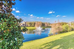 A serene outdoor setting with a pond, a fountain, and a well-maintained lawn. - 1st floor condo w/ basketball court, gym, sauna, shared pools, near theme parks (Davenport)
