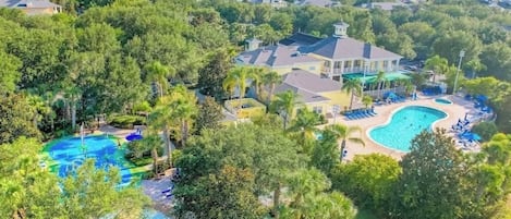 Un quartier résidentiel comprenant plusieurs maisons, une grande piscine et une pelouse bien entretenue.
