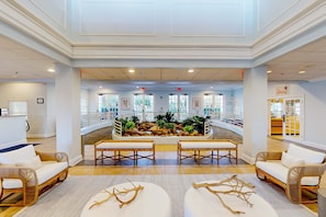 Eine geräumige Lobby mit einem zentralen Wasserspiel, Sitzbereichen und Blick ins Freie.