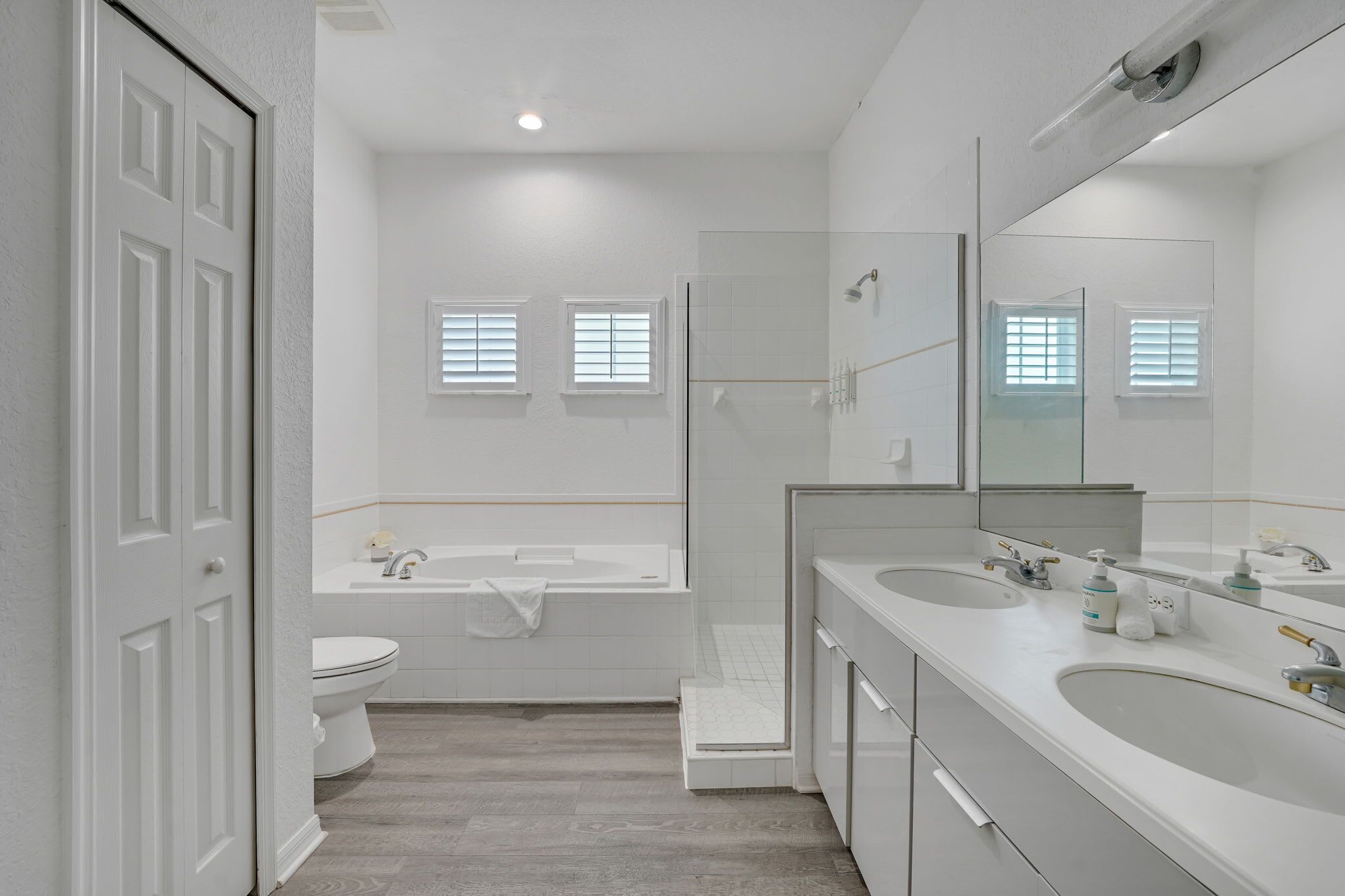 Une salle de bain moderne équipée d’une baignoire, de toilettes et d’un meuble-lavabo à deux vasques.