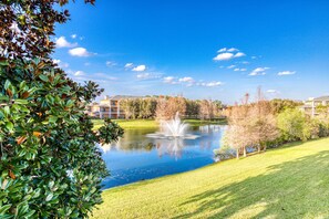Ein friedlicher Park mit Teich, üppigem Grün und blauem Himmel.