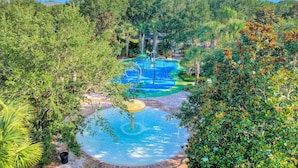 A water park with a pool, slides, and a circular water feature surrounded by lush greenery. - Beautiful condo with pool, hot tub, central AC & W/D - short drive to Disney (Davenport)