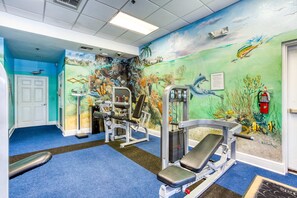 A gym with blue carpet, exercise equipment, and an underwater mural. - 3rd floor condo w/ restaurant, balcony, pools, basketball court, tennis court (Davenport)