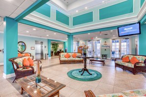 A spacious lobby with teal walls, wicker furniture, and a central table. - 3rd floor condo w/ restaurant, balcony, pools, basketball court, tennis court (Davenport)