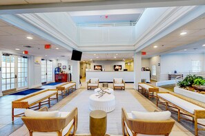 Eine großzügige Lobby mit hoher Decke, mehreren Sitzbereichen und einer Rezeption.
