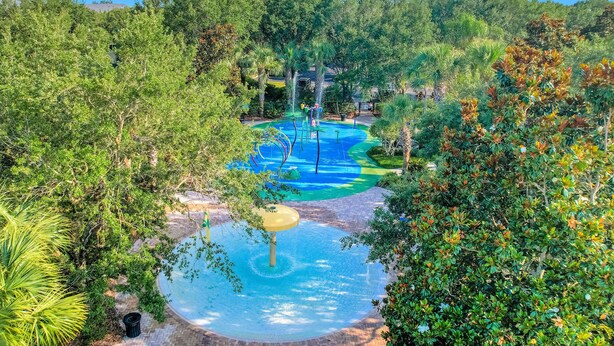 Parque acuático con piscina, toboganes y una fuente circular rodeada de vegetación exuberante.