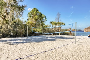 A beach volleyball court with a net, surrounded by trees and a view of the ocean. - 1st floor condo near theme parks, shared pools, basketball court, sauna, patio (Davenport)