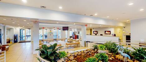 A spacious lobby with a central water feature, seating areas, and a reception desk.
