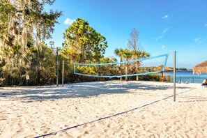 A beach volleyball court with a net, surrounded by trees and a fence. - First floor condo w/ tennis court, restaurant, pools - near theme parks (Davenport)