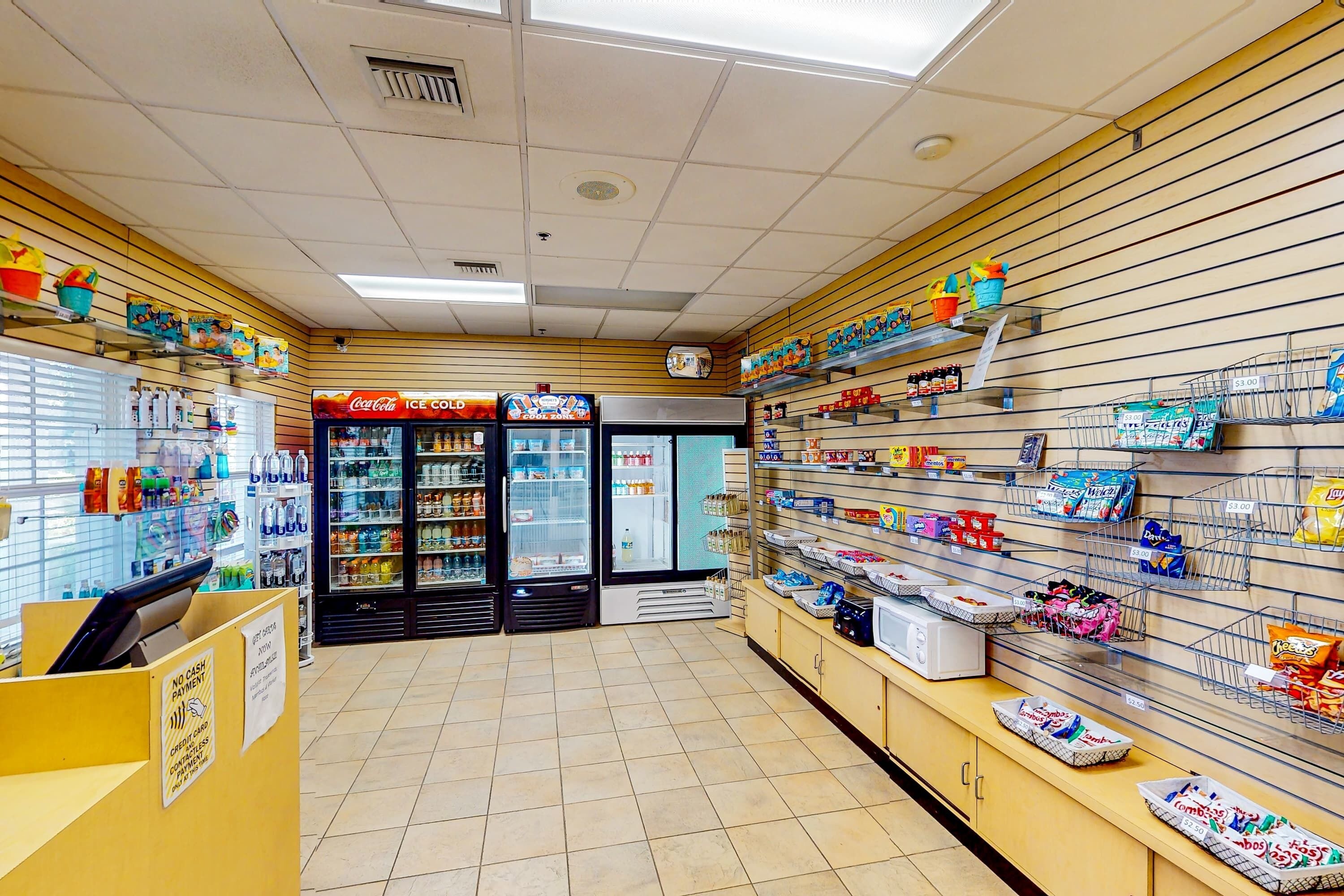 L'intérieur d'une épicerie, avec des étagères remplies de collations, un rayon réfrigéré et un congélateur à boissons Coca-Cola.