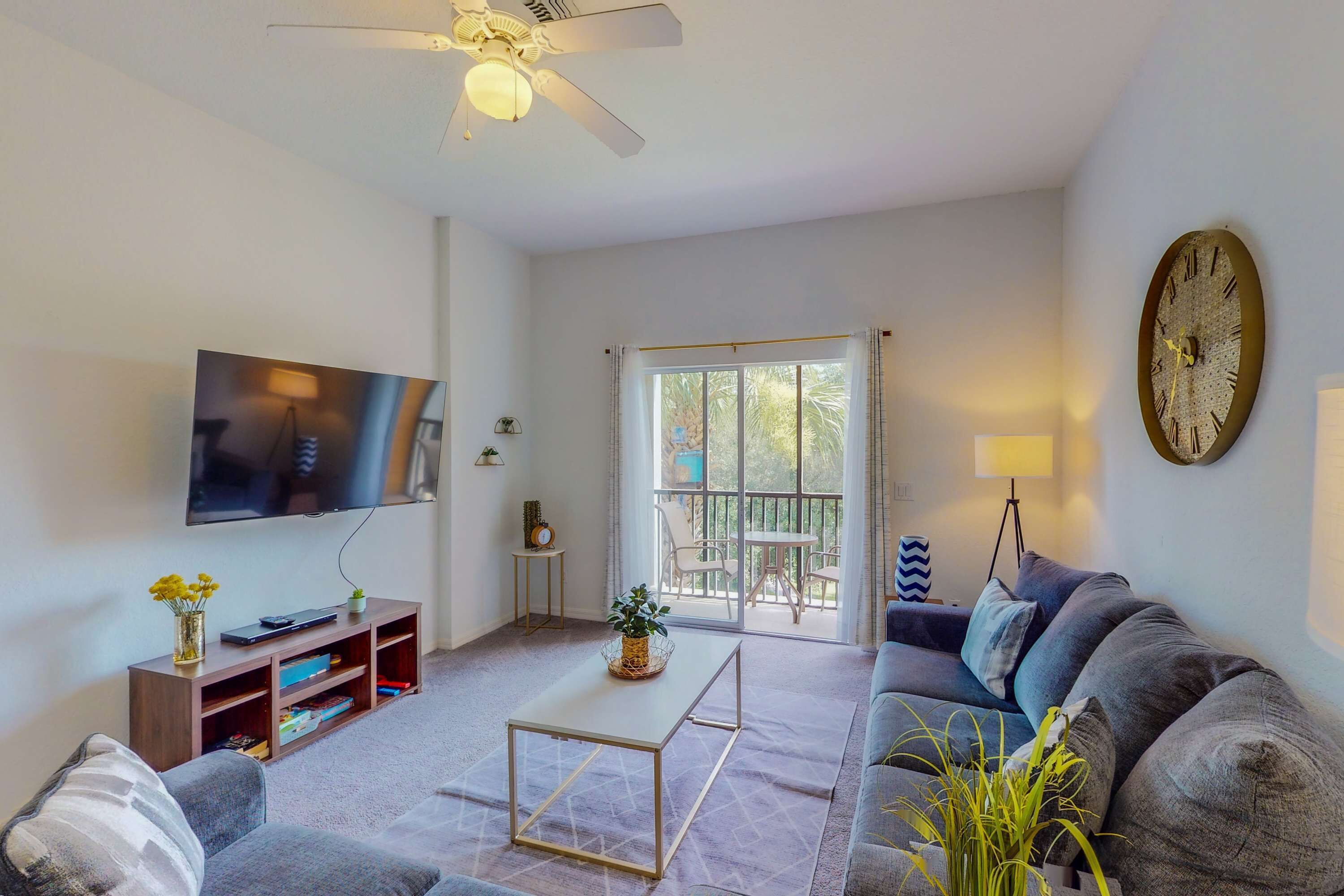 A living room with a sofa, coffee table, TV, and a ceiling fan.