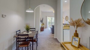 A dining area with a wooden table and chairs, a hanging light fixture, and a framed sign on a sideboard. - 2nd-floor condo with balcony, sauna, basketball court, on-site restaurant & pool (Davenport)