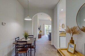 Uma área de refeições com mesa e cadeiras de madeira, luminária pendente e um letreiro emoldurado sobre um aparador.