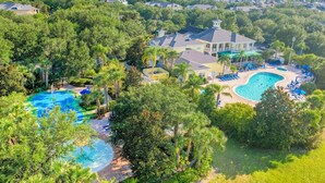 A residential area with multiple houses, a large swimming pool, and lush greenery. - 1st floor condo near theme parks, tennis court, patio, restaurant, shared pools (Davenport)
