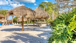 A beach with thatched umbrellas, lounge chairs, and a sandy area. - 2nd floor condo w/ balcony, basketball court, near theme parks, tennis court (Davenport)
