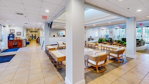 Eine geräumige Lobby mit einer langen Rezeption, gemütlichen Sitzbereichen und Blick ins Freie durch große Fenster.