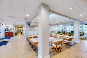 Eine geräumige Lobby mit einer langen Rezeption, gemütlichen Sitzbereichen und Blick ins Freie durch große Fenster.