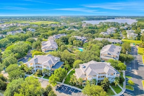 A residential area with houses, a swimming pool, and a lake in the background. - 1st floor condo w/ gym, pools, basketball court, sauna, limited-mobility access (Davenport)