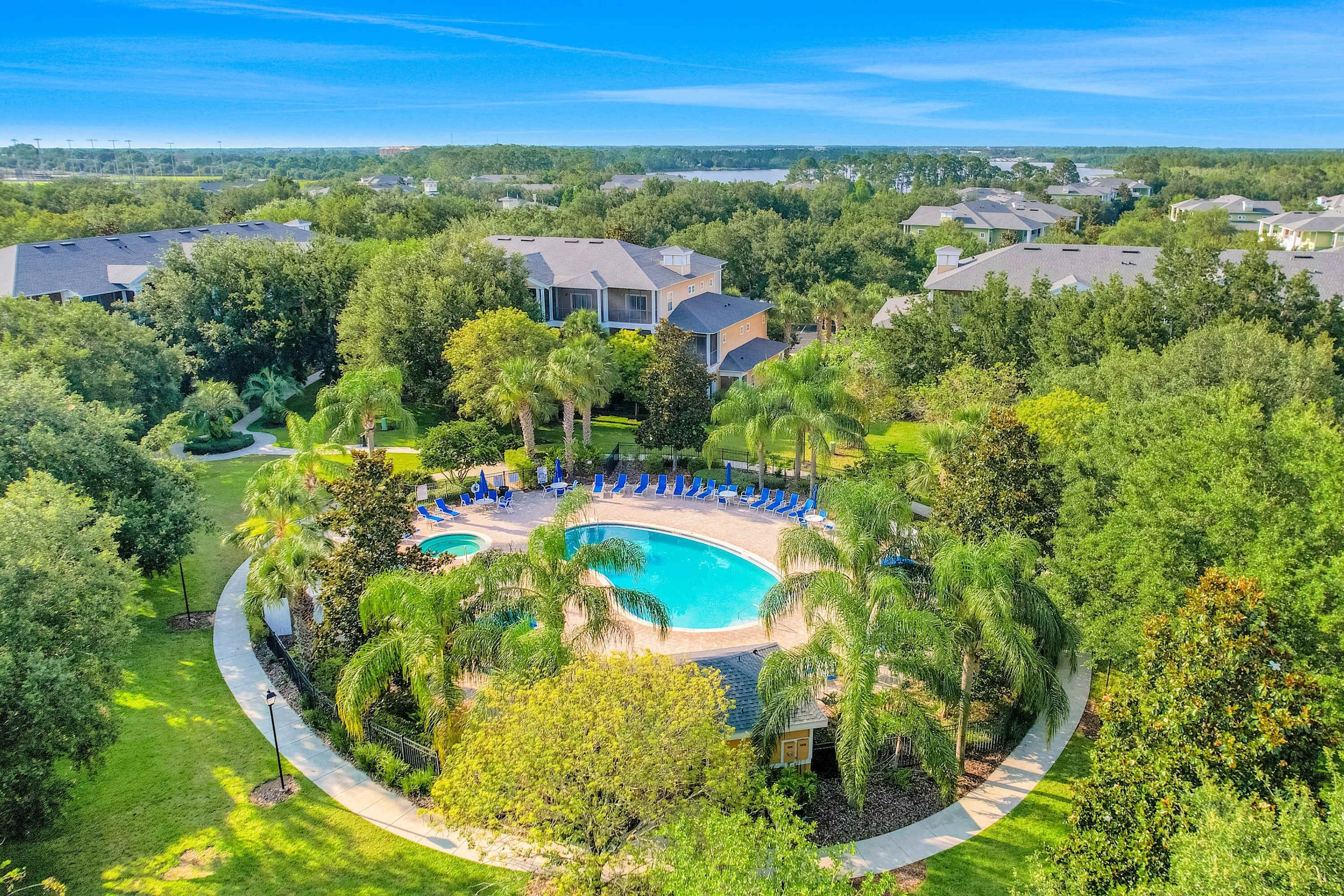 Zona residencial con piscina rodeada de palmeras y un sendero.