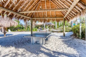 A beachside pavilion with a ping pong table, surrounded by sand and thatched umbrellas. - Second floor condo w/ gym, shared pools, tennis court - near theme parks (Davenport)