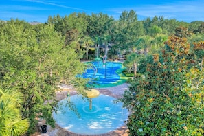 A water park with a pool, slides, and a circular water feature surrounded by lush greenery. - 3rd floor condo w/ basketball court, near theme parks, pools, gym, restaurant (Davenport)