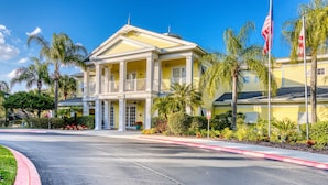 A yellow building with a central entrance, columns, and a balcony. - 2nd floor condo w/ gym, shared pools, tennis court, balcony, sauna (Davenport)