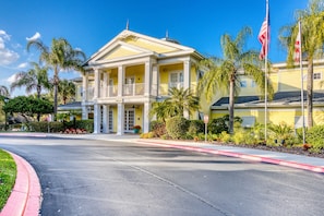 A yellow building with a central entrance, columns, and a balcony. - 2nd floor condo w/ gym, shared pools, tennis court, balcony, sauna (Davenport)