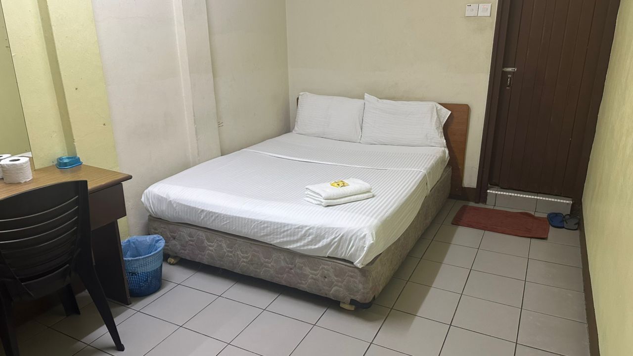 A small, clean room with a bed, a desk, and a chair.