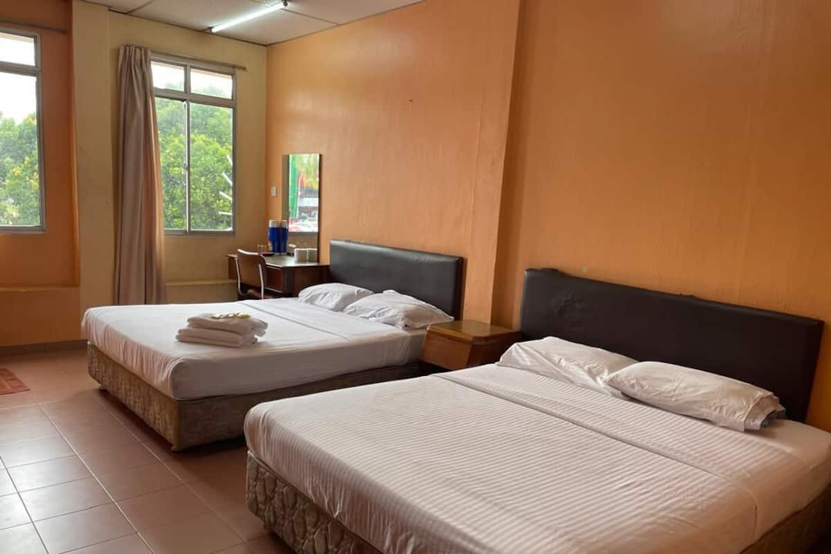 A hotel room with two beds, a desk, a chair, and a window with curtains.