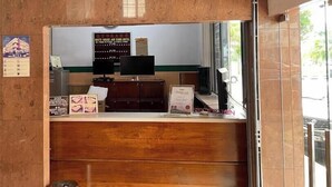Un comptoir d’accueil avec un ordinateur, un panneau encadré et une poubelle.