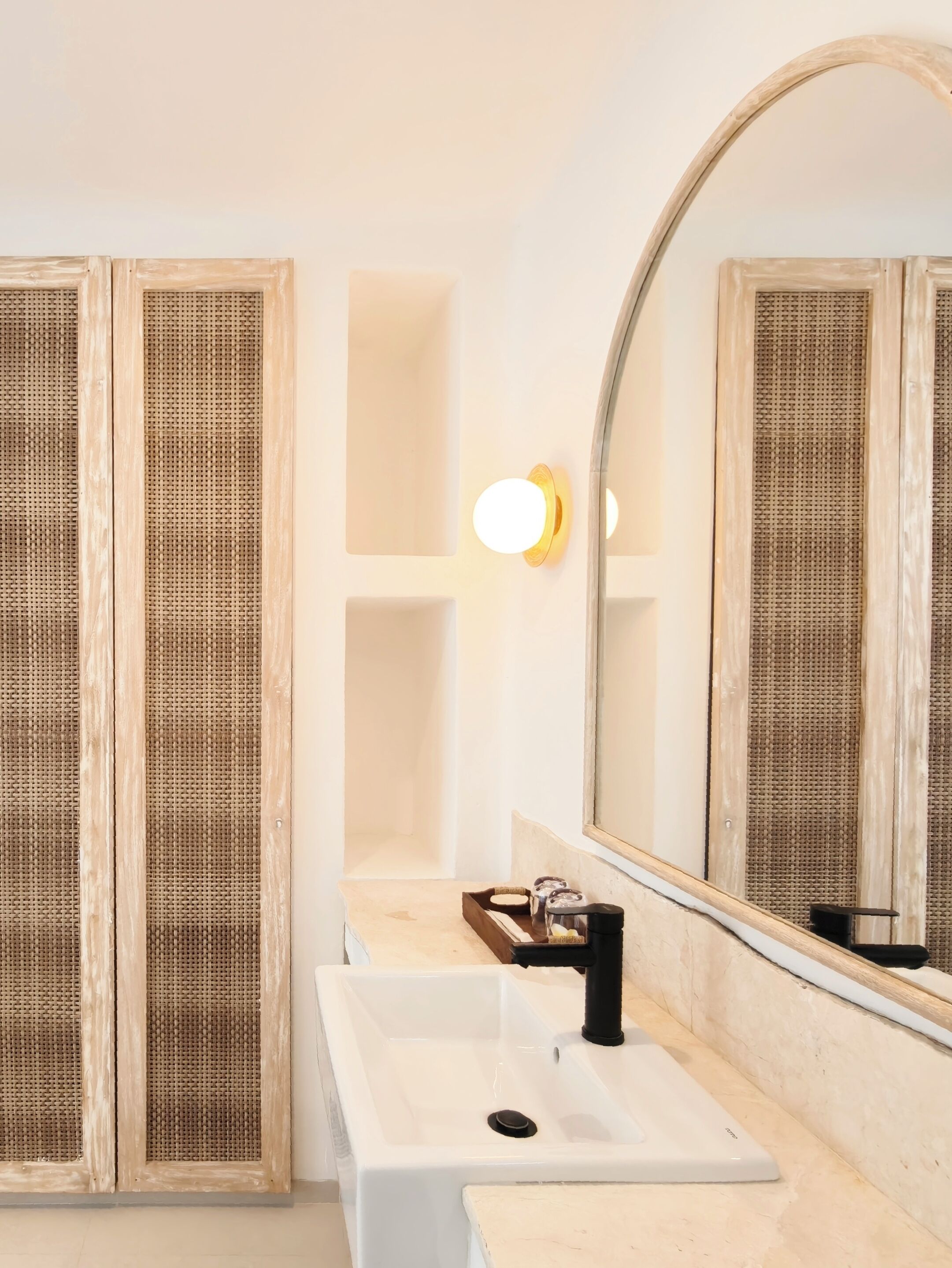 A bathroom with a white sink, a mirror, and a wall-mounted light fixture.