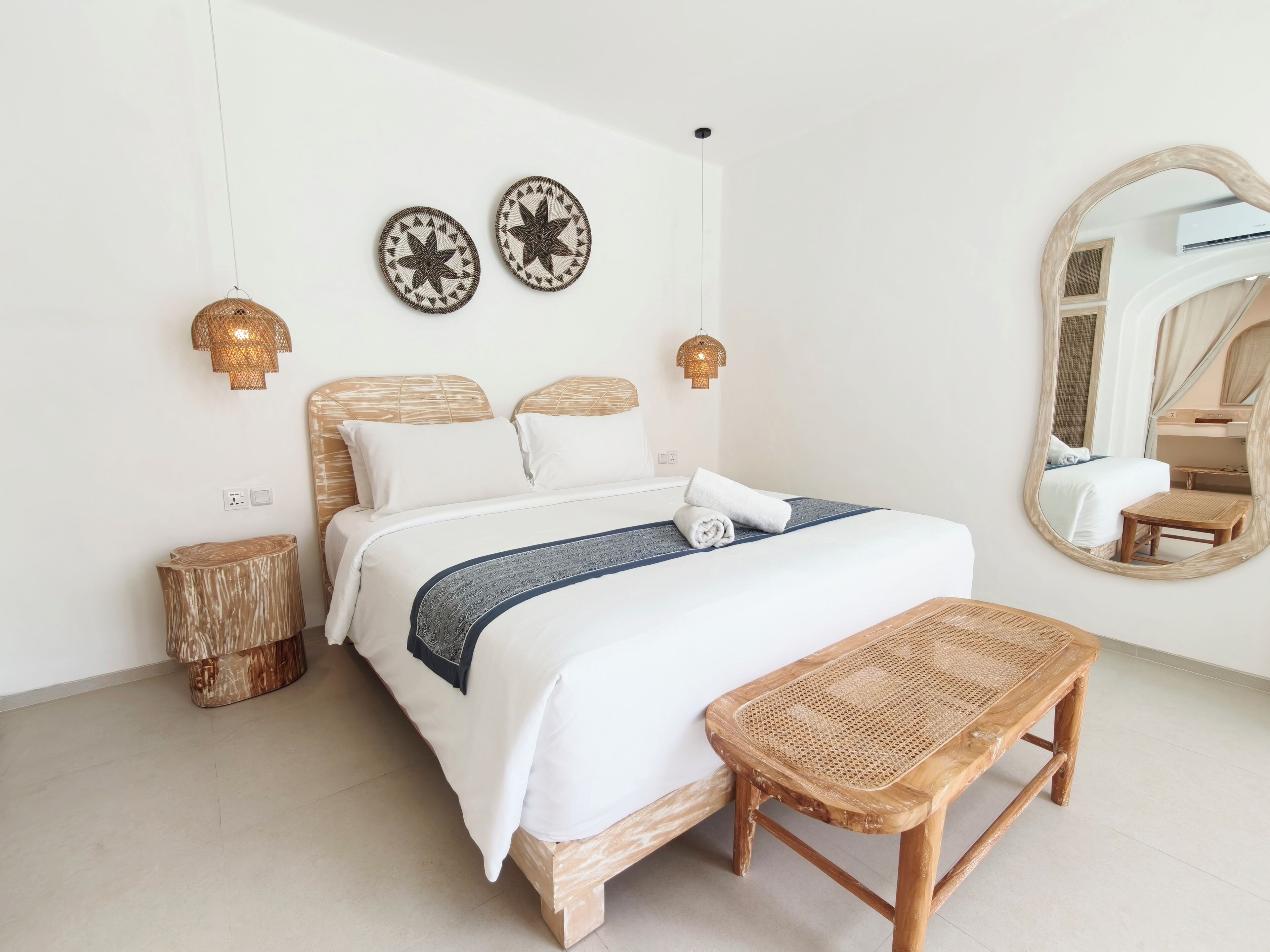 Een keurig opgemaakt slaapkamer met een bed, nachtkastje en een grote spiegel.