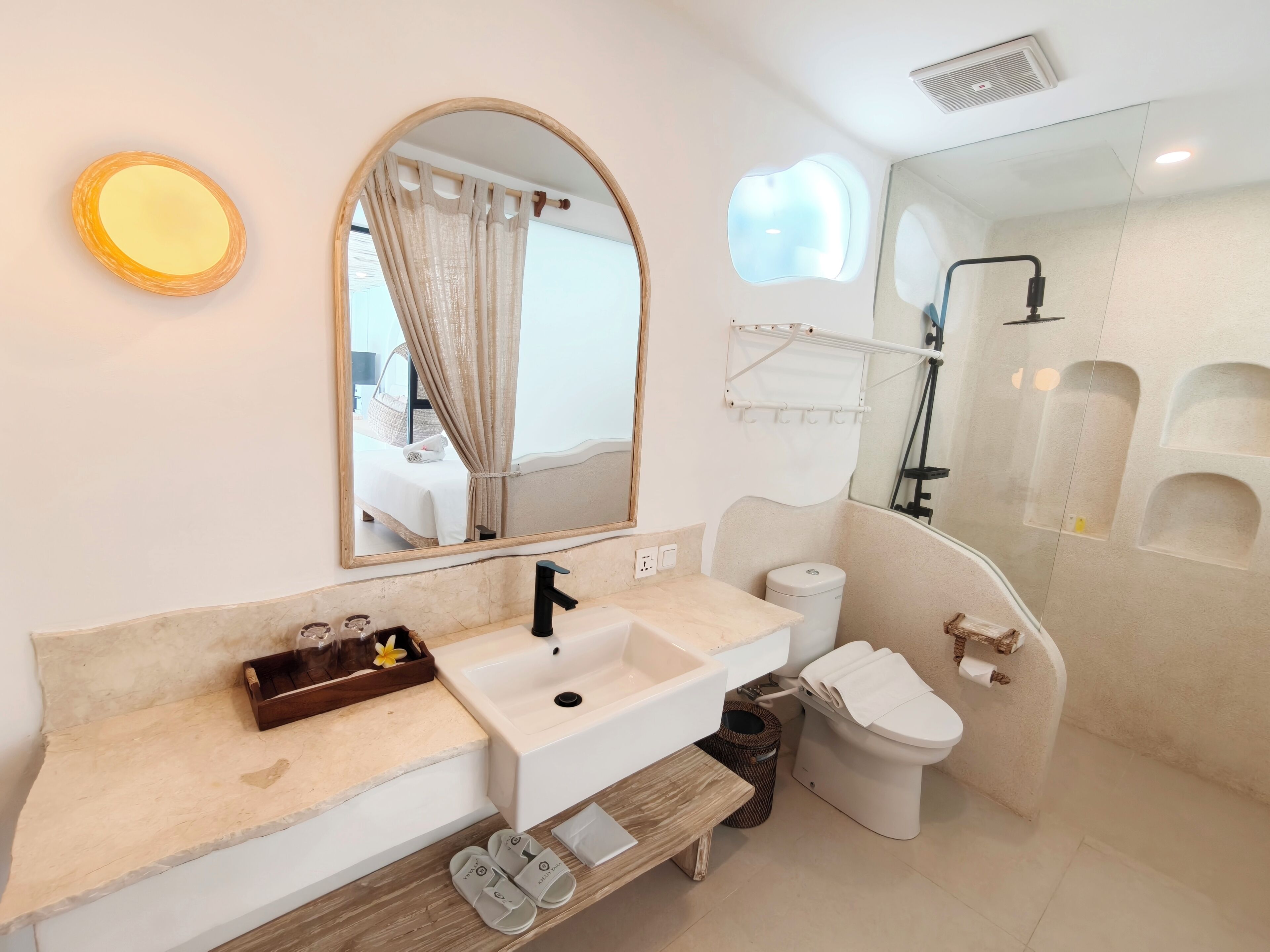 Une salle de bain moderne équipée d’un meuble-lavabo, d’un lavabo, d’un miroir, de toilettes et d’une douche.