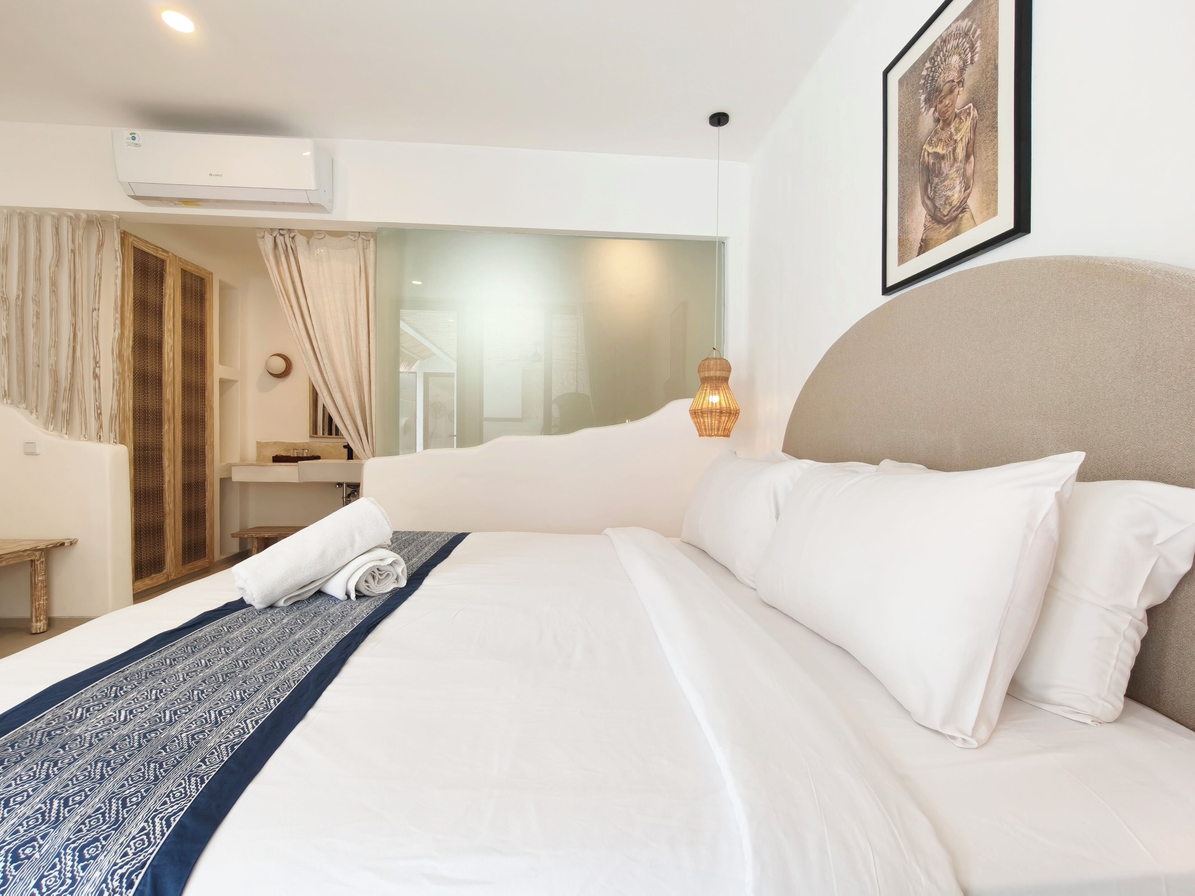 Una habitación de hotel con una cama grande, una mesita de noche, un espejo y una ventana con cortinas.