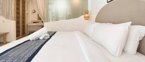 Una habitación de hotel con una cama grande, una mesita de noche, un espejo y una ventana con cortinas.