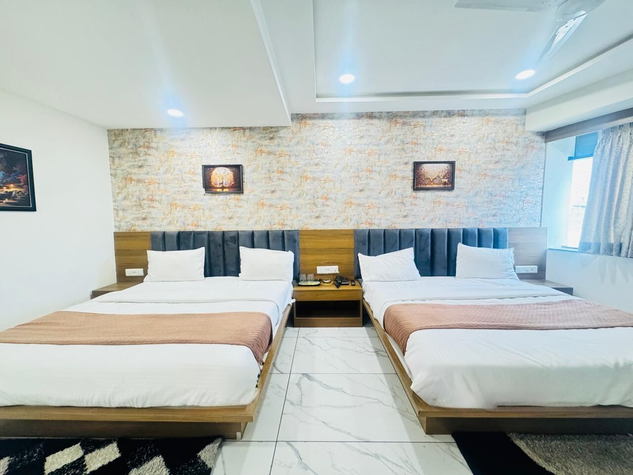 Una camera d'albergo con due letti, un muro in pietra e vista sull'esterno.