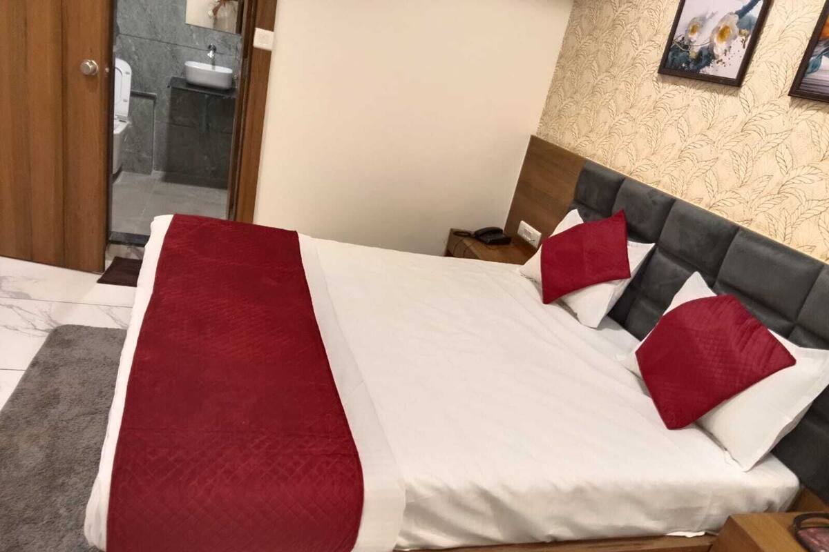 A bed with a red and white bedspread, a wooden headboard, and a nightstand with a phone.