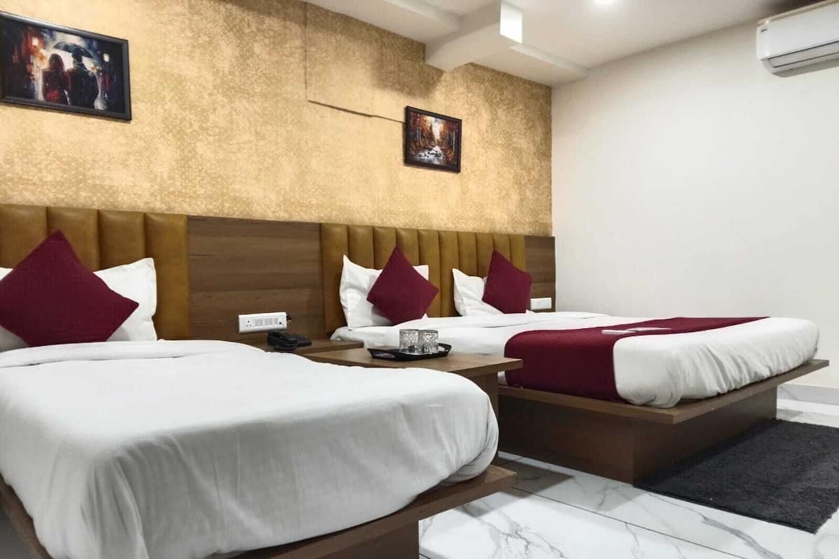 A hotel room with two beds, marble flooring, and a textured wall.