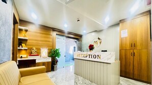 A reception area with a marble counter, wooden cabinets, and a sofa. - Hotel Long Stay (Ahmedabad)