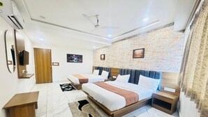 A hotel room with a large bed, two bedside tables, a ceiling fan, and a marble floor. - Hotel Long Stay (Ahmedabad)