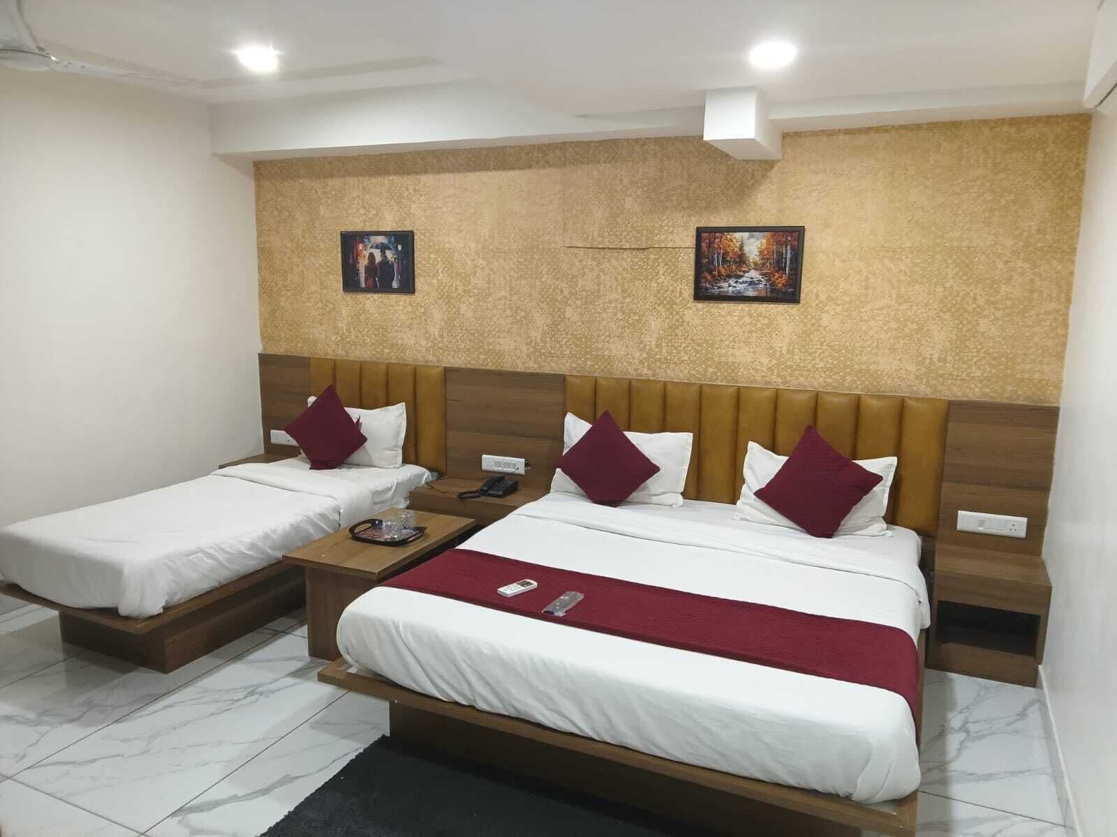 Een hotelkamer met twee eenpersoonsbedden, een houten hoofdbord, een marmeren vloer en twee schilderijen aan de muur.