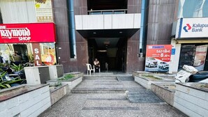 A building entrance with a Raymond Shop on the left and a Kalupur Bank on the right. - Hotel Long Stay (Ahmedabad)