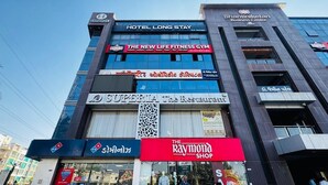 A multi-story building with various businesses including a hotel, a fitness center, a restaurant, and a shop. - Hotel Long Stay (Ahmedabad)