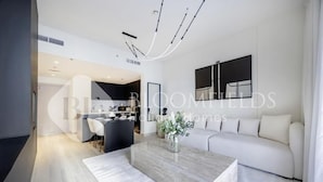 A modern living room with a sofa, a coffee table, and a dining area with chairs. - Bloomfields Formula 1br In Water (Abu Dhabi)