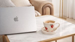Un laptop su un tavolo in marmo con una tazza di caffè accanto.