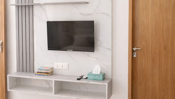 Una camera da letto moderna con TV a parete, una parete in marmo, una porta in legno e un comodino con un portatovaglioli.