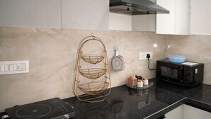 Una cucina con un piano di lavoro nero, un forno a microonde, un tostapane e un cesto portabiancheria a parete.