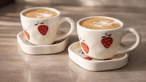 Due tazze bianche con decorazioni a fragola su un tavolo.