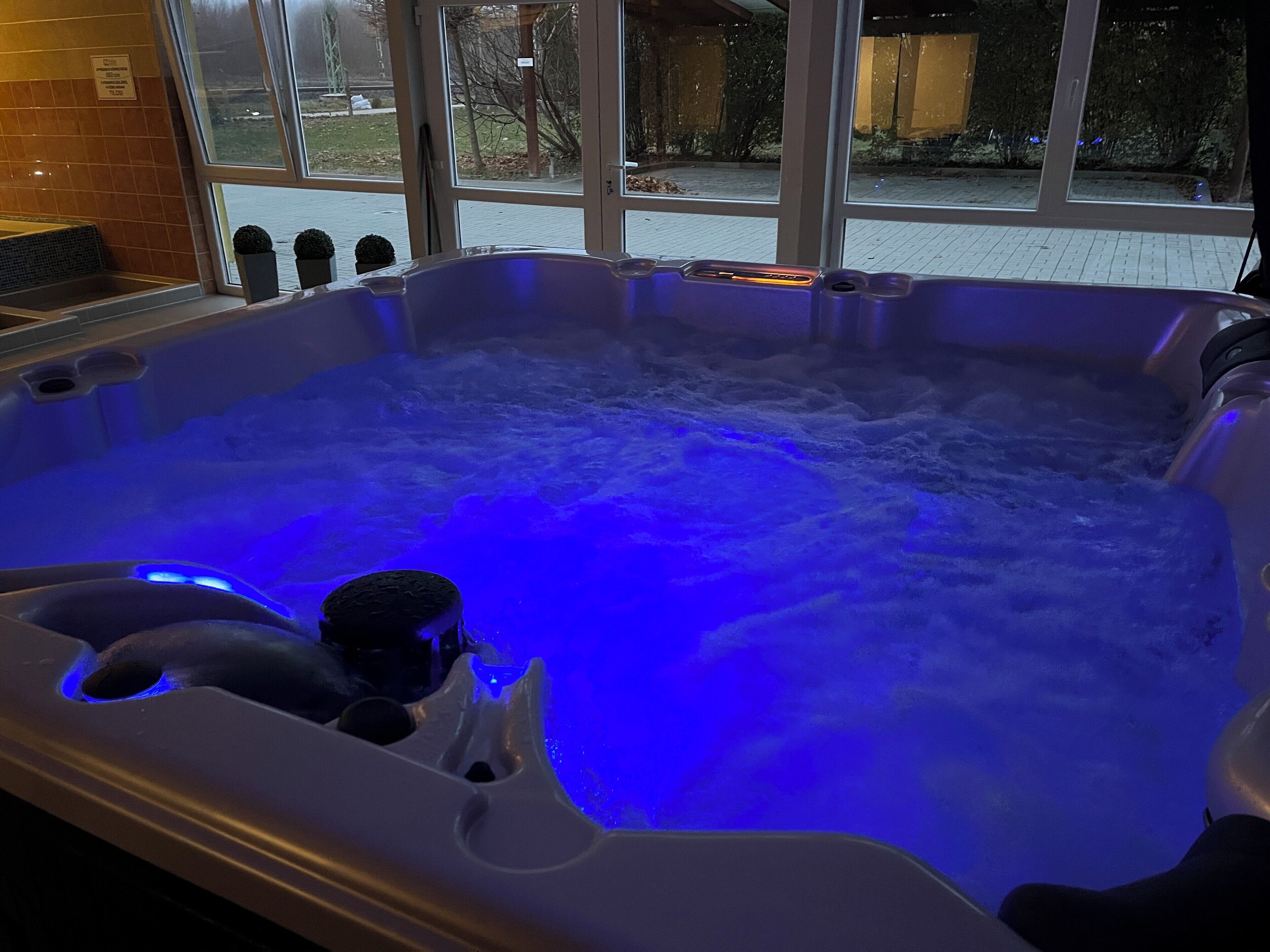 A hot tub with blue lighting, visible through a window.